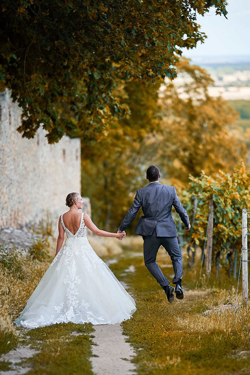 Bräutigam springt vor Freude auf Weinbergweg bei Hochzeitsshooting