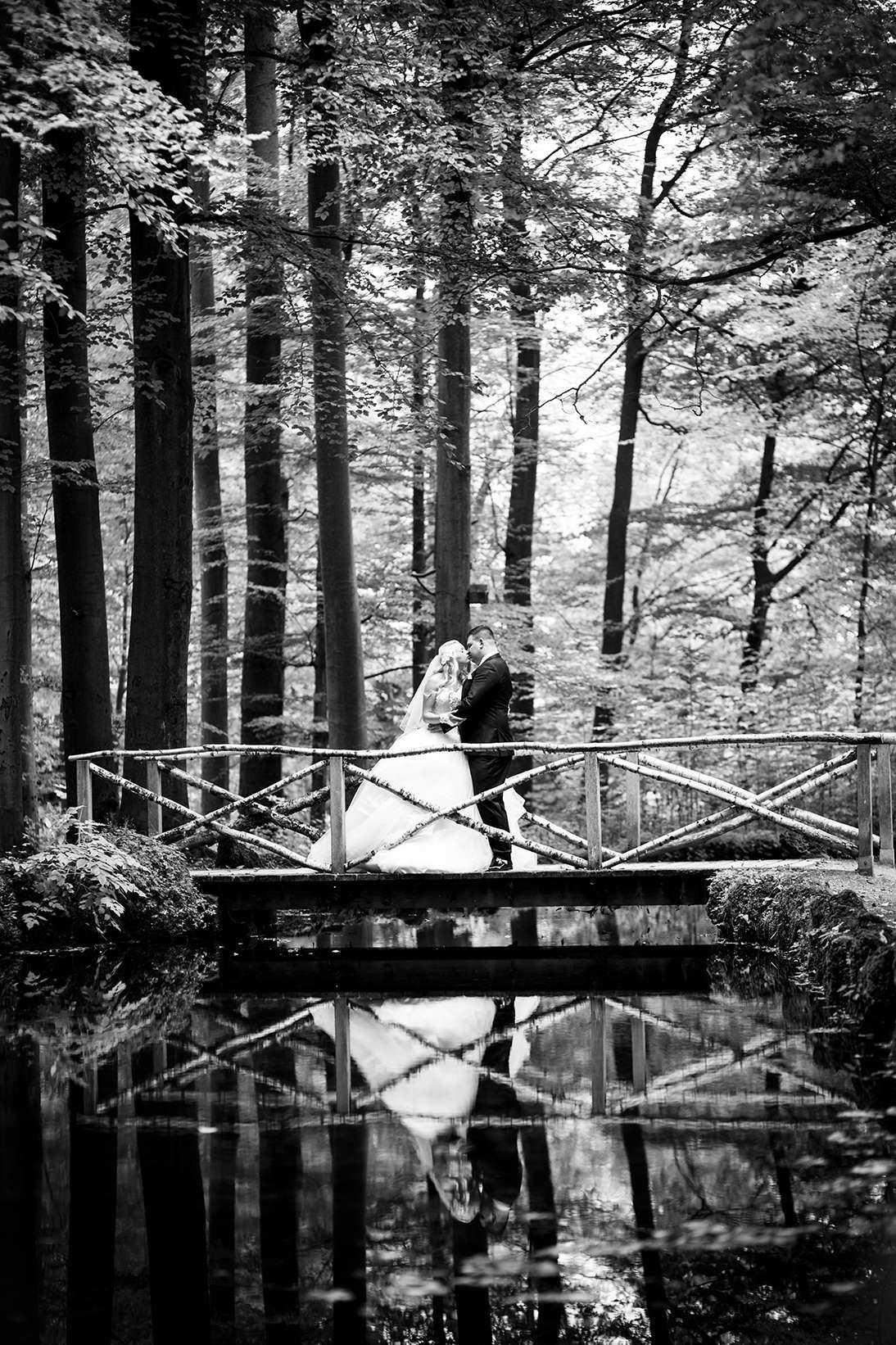 Romantisches Brautpaar in einem Wald, innige Umarmung in Schwarz-Weiß.