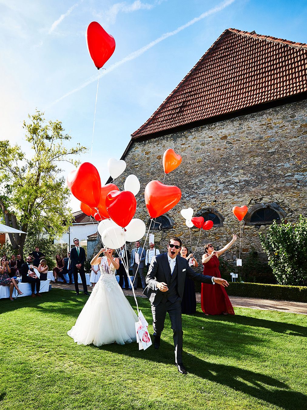 Hochzeitsgäste lassen Luftballons im Garten steigen